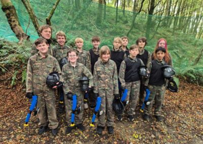 Group of kids in camouflage gear holding paintball guns, ready for action in a forest setting.