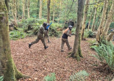 People playing paintball in a forest, running and aiming their guns