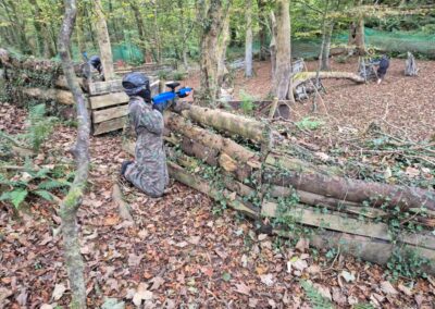 Person playing paintball in a wooded arena, part of the Gallery.