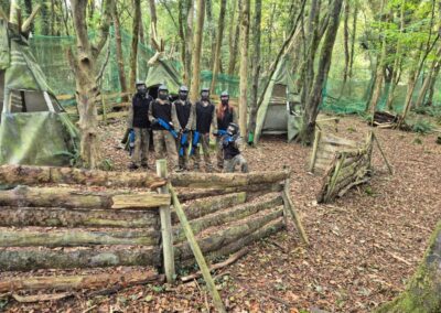 Group of people playing paintball in a wooded area, part of a paintball game. Outdoor activities.