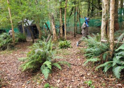 Players in a paintball game in a forest setting, part of a gallery of outdoor activities.