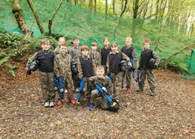 Children in camouflage gear with laser tag guns in a wooded area.