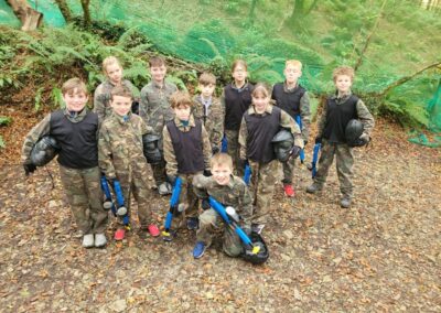 Group of children in camouflage gear with paintball guns, ready for a game.